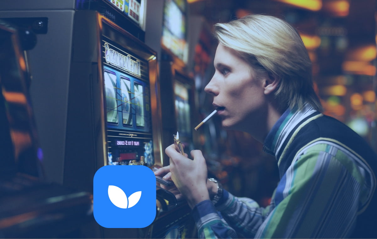 Мужчина смотри в игровой автомат и курит